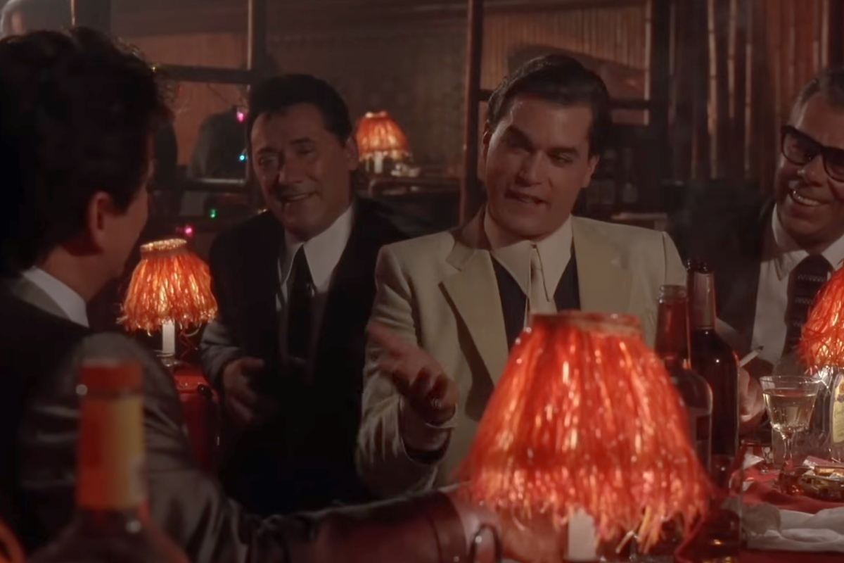 Ray Liotta in una scena di 'Quei bravi ragazzi' seduto in un locale in compagnia di altre persone