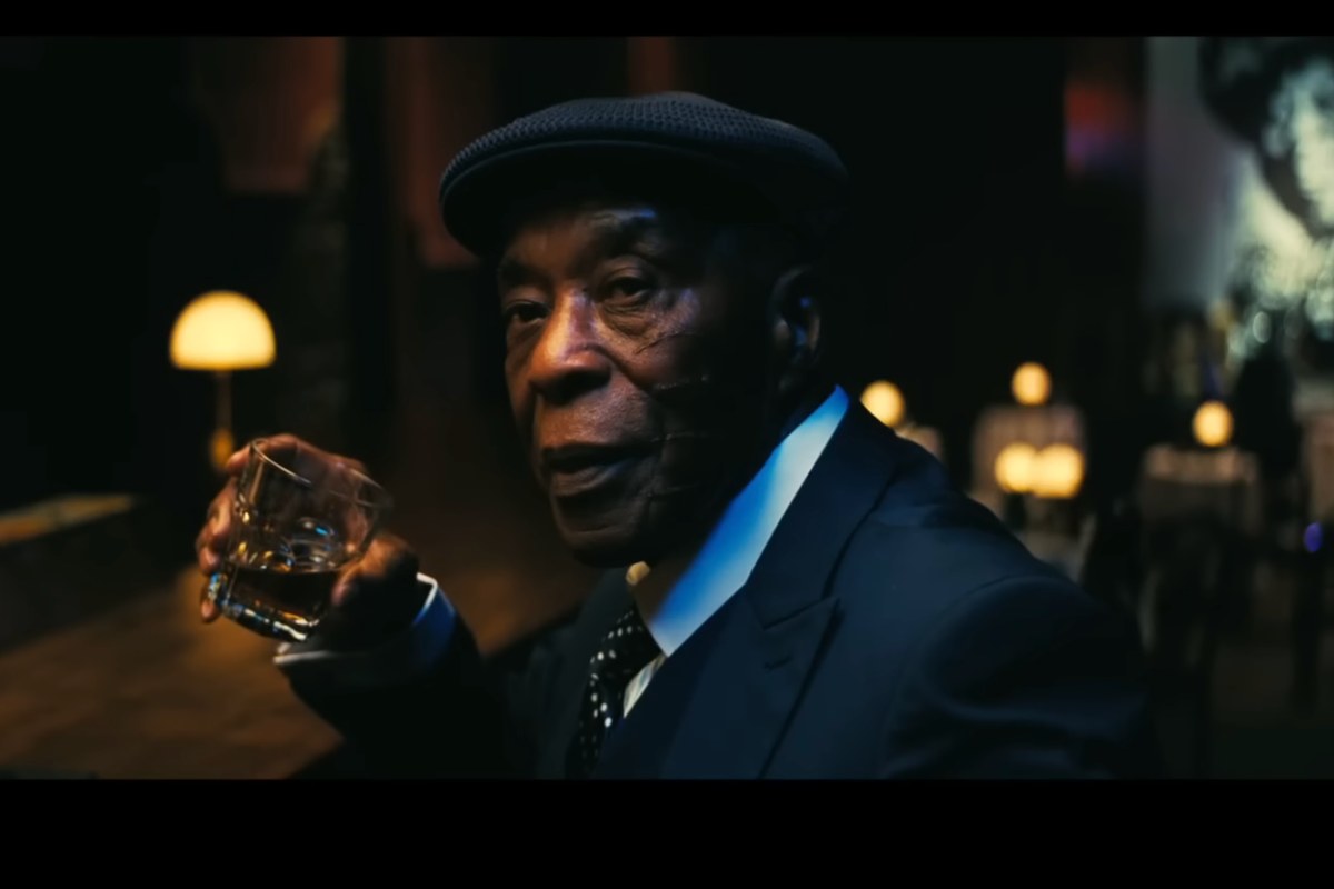 Un uomo afroamericano seduto in un locale voltato di lato per guardare qualcosa, in una scena del film Sinners