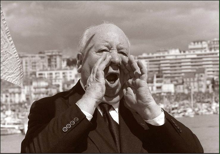 Alfred Hitchcock imparte ordini sul set con entrambe le mani alla bocca per aumentare il suono della voce