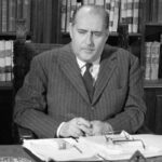 Roberto Rossellini seduto alla scrivania con alle spalle una libreria