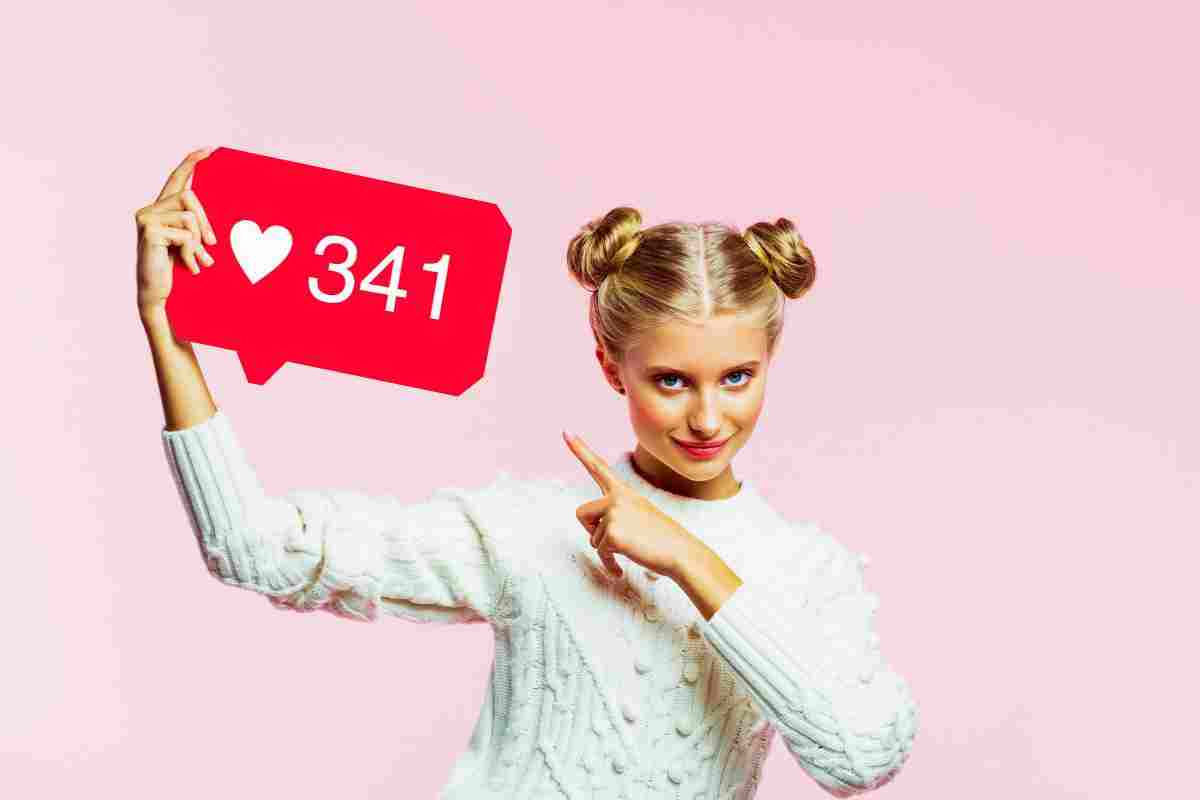 Ragazza bionda con in mano il cartello dei like di Instagram e il valore di 341